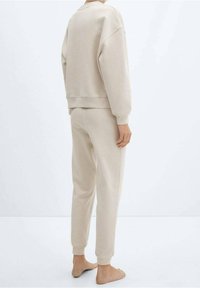 Sudadera beige y pantalones de chándal a juego, hechos de una tela suave, con un corte relajado, puños acanalados y un diseño simple.