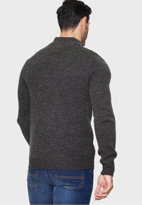 Maglione a maglia grigio scuro con colletto alto e polsini a costine. Il tessuto presenta un motivo testurizzato adatto per un abbigliamento casual.