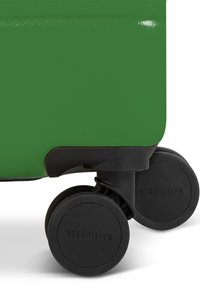 Groene koffer met een gladde afwerking, met een stevige zwarte basis en twee duurzame, roterende wielen met het label "ETERNITIV."