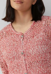 Rode en witte gebreide cardigan met een open weefpatroon, ronde halslijn en zilveren knopen aan de voorkant. Zachte textuur en lichtgewicht ontwerp.