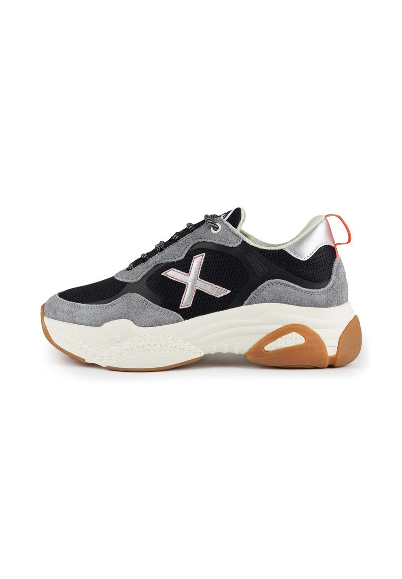 Schwarzer und grauer Sneaker mit einem Obermaterial aus Wildleder und Mesh, weißem Zwischensohlen, Gummi-Laufsohle und einem reflektierenden silbernen Fersenakzent.