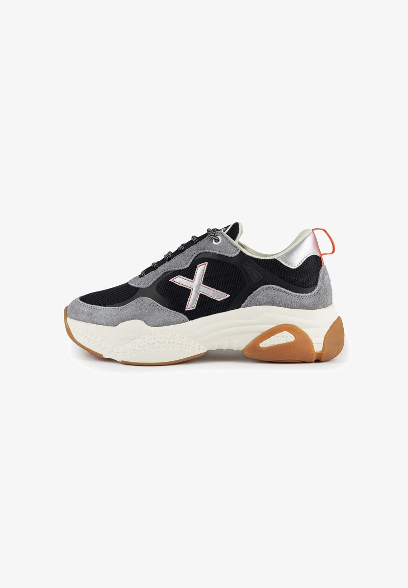 Schwarzer und grauer Sneaker mit einem Obermaterial aus Wildleder und Mesh, weißem Zwischensohlen, Gummi-Laufsohle und einem reflektierenden silbernen Fersenakzent.