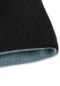 Schwarzer Strickstoff mit sichtbarer Stichstruktur zeigt einen hellblauen Innenfutter entlang einer gefalteten Kante auf einem weißen Hintergrund.