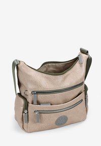 Bolso de hombro de color beige claro, fabricado en material sintético texturizado, con tres bolsillos frontales con cremallera, detalles en verde y un parche redondo con el logo.