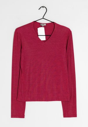 Halenka s dlouhým rukávem a véčkovým výstřihem v živé růžové barvě. Vyrobena z hladké, mírně texturované látky. Má rovný lem a připojenou visačku.