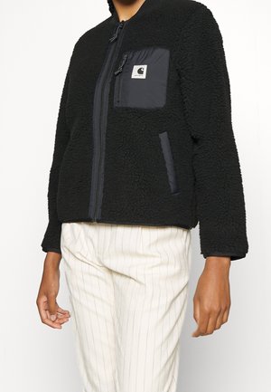 Czarna polarowa kurtka na zamek z kontrastową kieszenią z czarnego materiału i akcentami z tkaniny, z teksturowaną powierzchnią i luźnym fasonem.