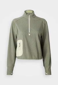 Pullover verde claro com gola alta, fecho de meio zíper, padrão texturizado e um bolso creme em contraste com zíper. Acabamento branco na bainha.