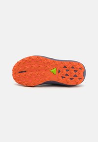 Trail running shoe outsole with an orange rubber surface, featuring multi-directional lugs for traction. Includes green accent detail.