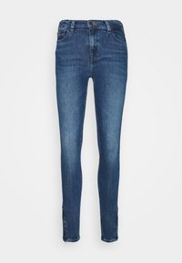 Pantalones vaqueros ajustados de mezclilla azul oscuro, con una cintura de altura media, diseño de cinco bolsillos y un leve desgastado en el dobladillo para añadir un detalle extra.