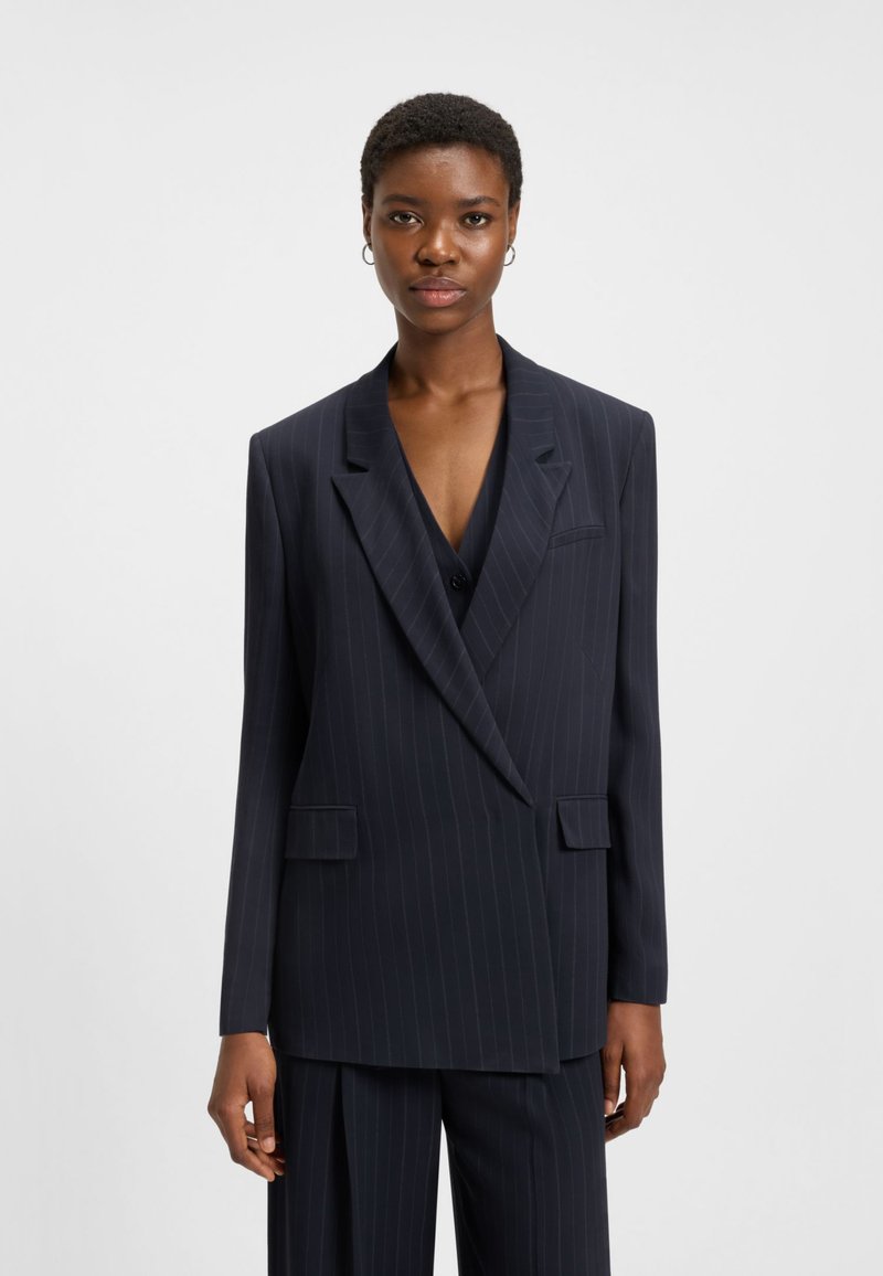 Navy pinstripe blazer with a tailored fit, featuring wide lapels, double-breasted closure, and side pockets, paired with matching trousers.