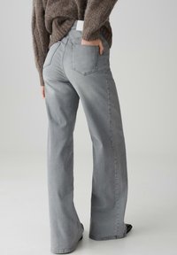 Jeans in denim grigio con un taglio a gamba larga e vita alta. Presentano due tasche posteriori e una cintura semplice. Texture morbida con una tonalità uniforme.