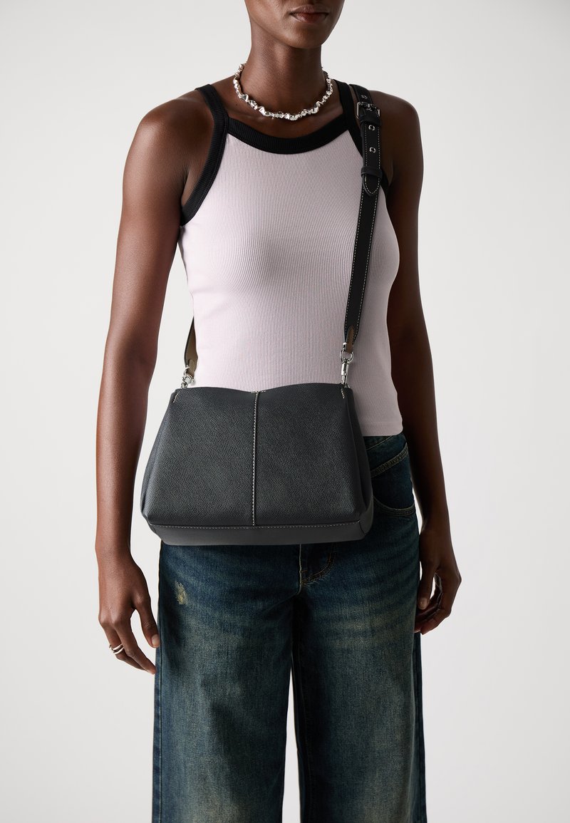 Borsa a tracolla in pelle grigia con forma strutturata, caratterizzata da una superficie liscia, accessori in argento e una tracolla regolabile.