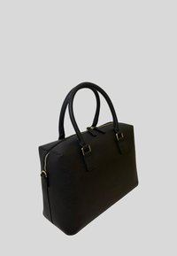 Borsa a mano in pelle nera con texture, dotata di due manici arrotondati e cerniera dorata su sfondo grigio chiaro.