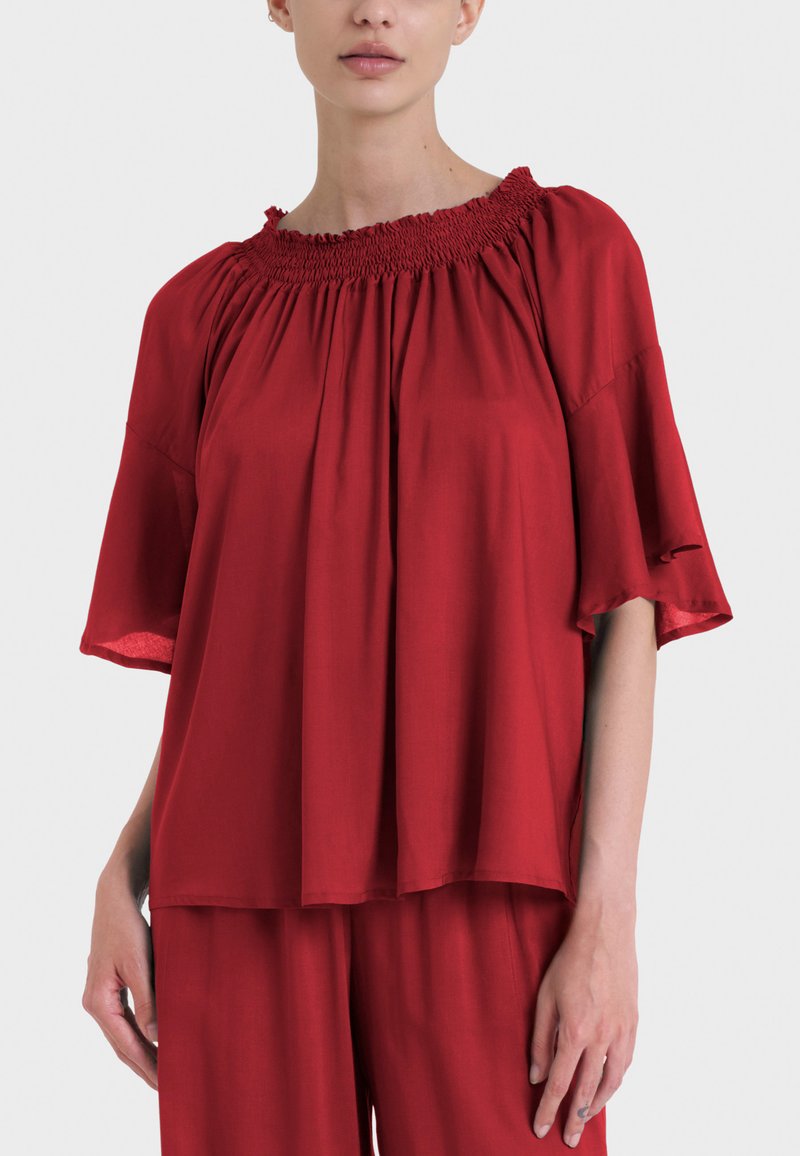 Top rosso ampio con scollatura arricciata e maniche corte larghe. Tessuto morbido e leggero con un design fluido.