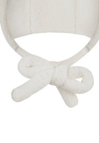 White fleece winter hat with ear flaps tied together in a knot under the chin.