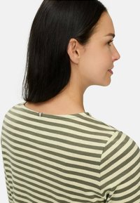 Grøn og creme stribet skjorte med rund halsudskæring og en lille detalje på ryggen. Stoffet virker blødt og let, velegnet til hverdagstøj.