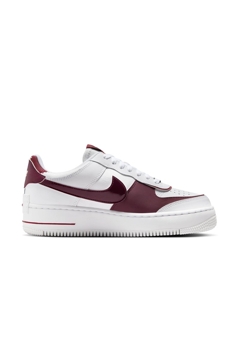 Nike Air Force 1-sneakers har en overdel i hvidt læder med mørkerøde accenter, en glat tekstur, perforeret tå og en gummisål med mønster for godt greb.
