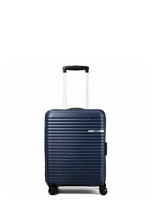 Valise rigide bleu foncé avec des rainures horizontales, quatre roues et une poignée télescopique noire déployée, debout sur fond blanc.