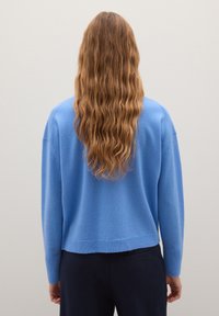 Lichtblauwe gebreide trui met een relaxte pasvorm, verlaagde schouders, geribbelde boorden en zoom. Glad textuur en een middellange silhouette.