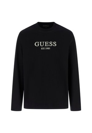 Svart långärmad tröja med broderad "GUESS EST.1981" logotyp i ljusgrått. Tillverkad av slät tyg, klassisk rund halsringning och standard passform.