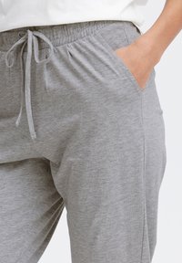 Grå joggebukser laget av myk bomullsblanding, med elastisk liv med snor, sidelommer og en avslappet passform.