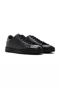Black leather sneakers with a smooth upper, lace closure, and textured black rubber midsole. Rounded toe and low-cut design.