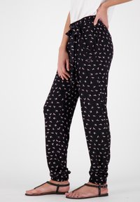 Svarta joggerbyxor med ett rosa fågelmönster, elastisk midja, knytning fram och mudd vid anklarna. Lättviktsmaterial.