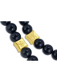 Bracciale con perle nere lucide, composto da perle sferiche nere e due accentuazioni quadrate dorate con disegni incisi.