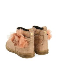 Botas rosas texturizadas con un acento de tul floral en el costado. Material suave y diseño de perfil bajo con una suela marrón claro. Cierre con cremallera en la parte trasera.