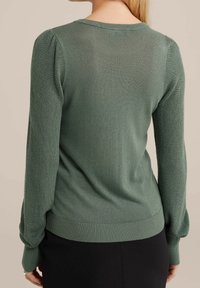 Grön stickad tröja med långa ärmar, rundad halsringning samt ribbade muddar och nederkant. Texturerad tyg med en mjuk finish.