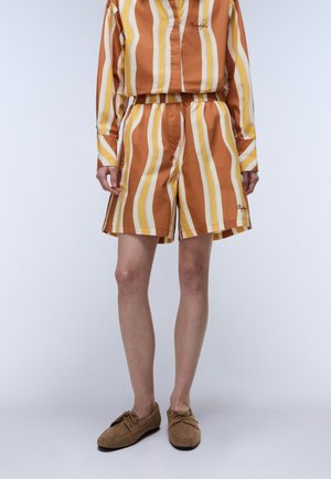 Krótki zestaw z pionowymi paskami w kolorach pomarańczowym, żółtym i białym. Wykonany z lekkiego materiału, wyposażony w elastyczną talię. Dołączone brązowe obuwie.
