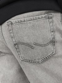 Grå denimjeans med en rektangulär bakficka som har en subtil sydd kurvdetalj. Tyget har en strukturerad yta.