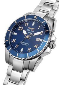 Edelstahlarmbanduhr mit blauem Zifferblatt, silbernen Indizes und einer Datumsanzeige. Die Lünette ist strukturiert, das Armband ist metallisch und poliert.