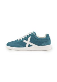 Sneaker blu in suede con lacci e dettagli bianchi. Presenta una suola in gomma bianca testurizzata e un design X bianco ben evidente sul lato.