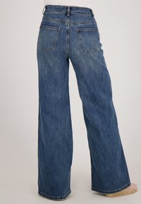 Blauwe wijde spijkerbroek van denimstof. Heeft een hoge taille, een vijf-pocket ontwerp en een subtiele wassing op het oppervlak.