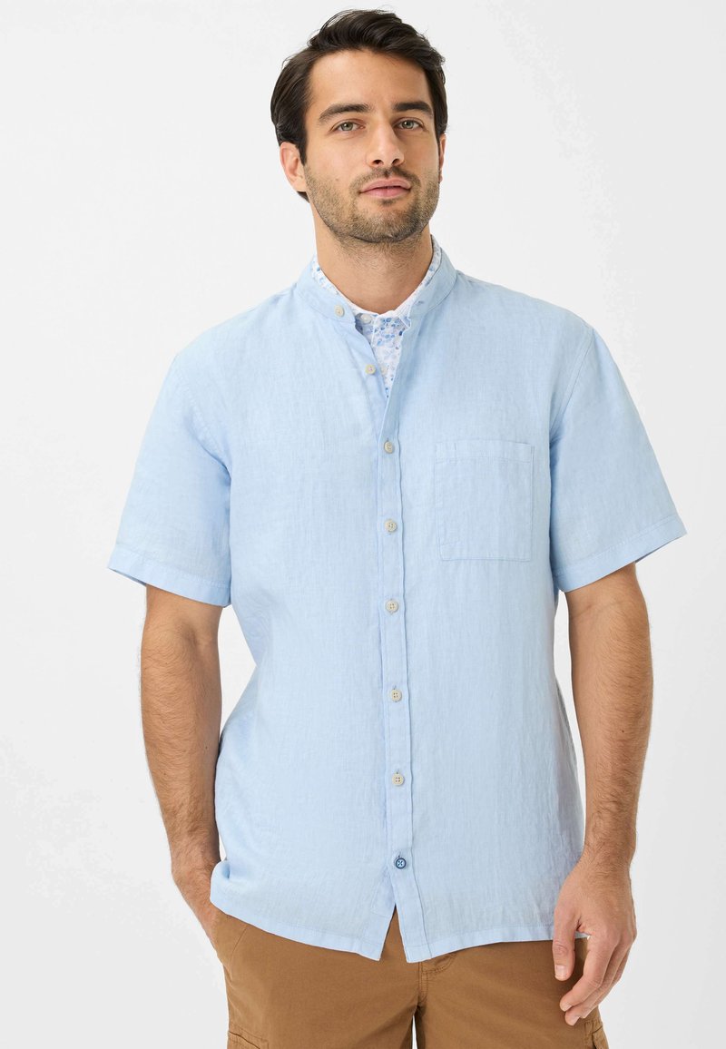 Camicia a maniche corte blu chiaro in tessuto testurizzato con colletto abbottonato e una tasca sul petto, dotata di bottoni chiari e una vestibilità morbida.