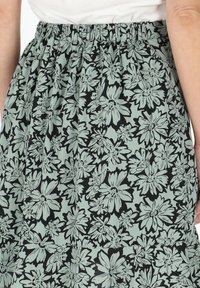 Gonna floreale realizzata in tessuto leggero; presenta una base nera con fiori verde menta; vita elastica; texture liscia con un design arricciato.