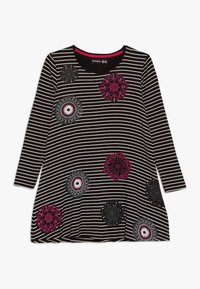 Czarna i biała tunika w paski z długim rękawem, ozdobiona kolorowymi haftowanymi kwiatowymi wzorami w kolorach różowym, czarnym i srebrnym na przodzie.