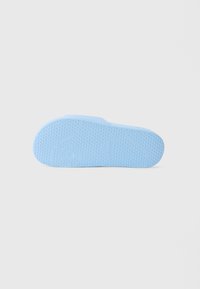 Talpa de sandală din cauciuc albastru deschis, cu textură pentru aderență și logo-ul Lacoste embosat, văzută de jos pe un fundal alb.