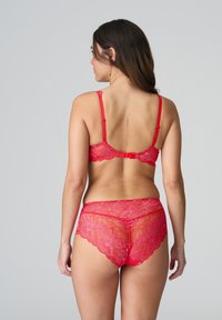 Rode kanten lingerieset met bloemmotieven; verstelbare bandjes op de bh; golvende randen op de bijpassende slipjes; doorschijnende textuur.