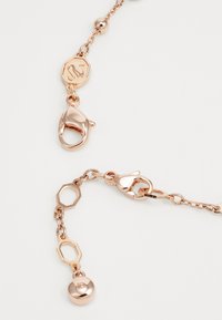 Corrente de ouro rosa com várias formas ligadas, apresentando um charme hexagonal e fechos de lagosta, textura suave com acabamento polido.