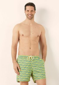 Costumi da bagno da uomo in un vivace giallo con un motivo a cactus. Presentano una vita elastica con cordino e tasche laterali. Tessuto leggero.