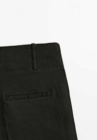 Pantalons en lin noirs avec un devant plat, dotés d'une taille avec passants de ceinture et d'une poche arrière unique. Design simple et texturé.