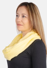 Yellow scarf made of lightweight, textured fabric, worn as a loop around the neck, enhancing a black top. Subtle, soft folds visible.