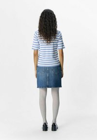 Top de rayas azul y blanco de manga corta combinado con una falda de mezclilla. Medias acanaladas grises y zapatos de plataforma negros completan el atuendo.