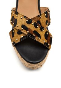 Sandales à plateforme en imprimé léopard avec semelle en cuir noir. Equipées de lanières croisées ornées de clous dorés et d'une semelle en jute tressée.