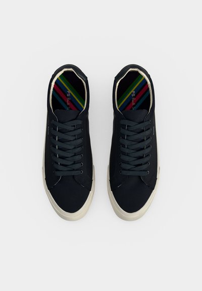 Paire de baskets basses noires avec semelles blanches et lacets noirs, vues de dessus sur un fond clair uni.