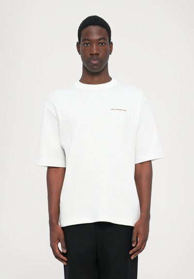 White, oversized cotton t-shirt with short sleeves and a crew neckline. Small, red logo detail on the left chest.