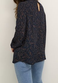 Blouse bleu marine avec un motif paisley bronze, manches longues et détail œillet au dos ; tissu léger avec une coupe décontractée.