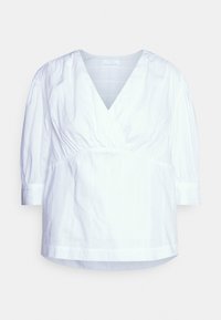 Blouse blanche à encolure en V, manches courtes bouffantes et taille froncée. Le tissu présente des rayures verticales subtiles et une texture lisse.